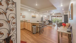 A spacious living area with a kitchen, wooden flooring, and a balcony with a view.