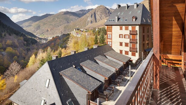 A hotel with multiple floors, a sloped roof, and a view of mountains in the background. - Val de Ruda Luxe 16 by FeelFree Rentals (Baqueira)