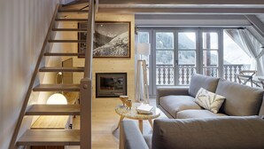 A modern living room with a wooden staircase, a fireplace, a sofa, and large windows offering a view of the outdoors. - Val de Ruda Luxe 16 by FeelFree Rentals (Baqueira)