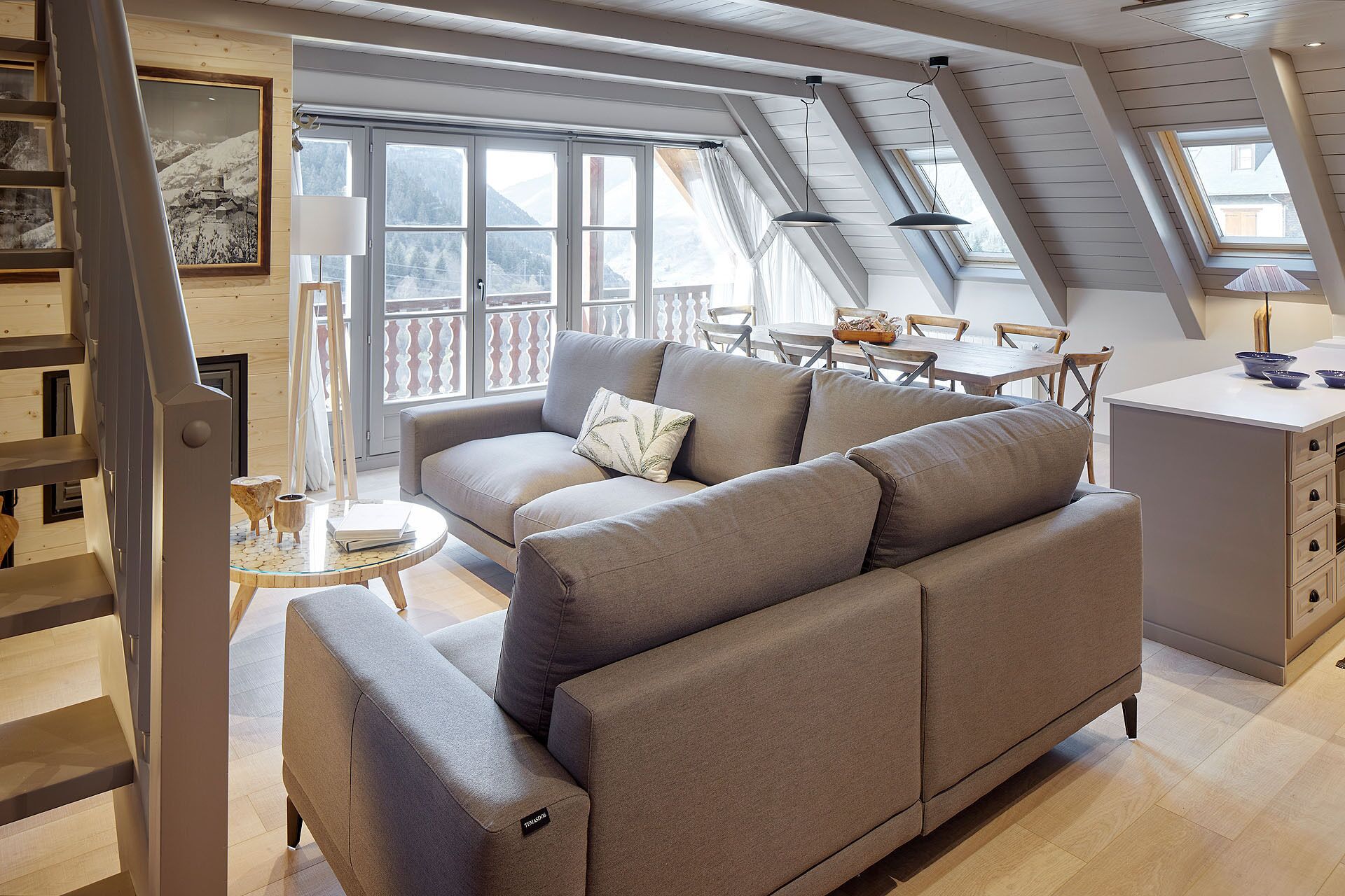 A cozy loft-style room with a sofa, dining table, and chairs.