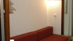 Una habitación pequeña con una cama de madera, una mesita de noche y una lámpara fijada a la pared.
