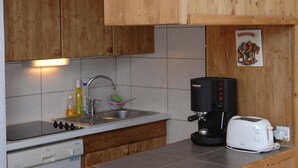 Una cocina con armarios de madera, cafetera, tostadora y un lavabo.