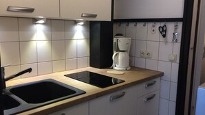 Eine moderne Küche mit einem schwarzen Induktionskochfeld, einer integrierten Spüle und einer Kaffeemaschine.