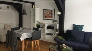 Ein Wohnzimmer mit Esstisch, Stühlen, einer Couch und einem Bücherregal.