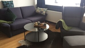 Ein Wohnzimmer mit grauem Sofa, einem runden Couchtisch mit Dekoration und einem grauen Sessel.