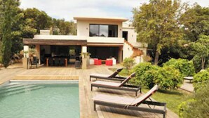 Une maison moderne dotée d’une piscine, d’un espace salon extérieur et d’un patio couvert.
