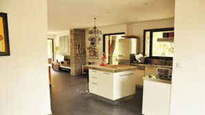 Une cuisine moderne avec des meubles blancs, un îlot central et un coin repas comprenant une table et des chaises.
