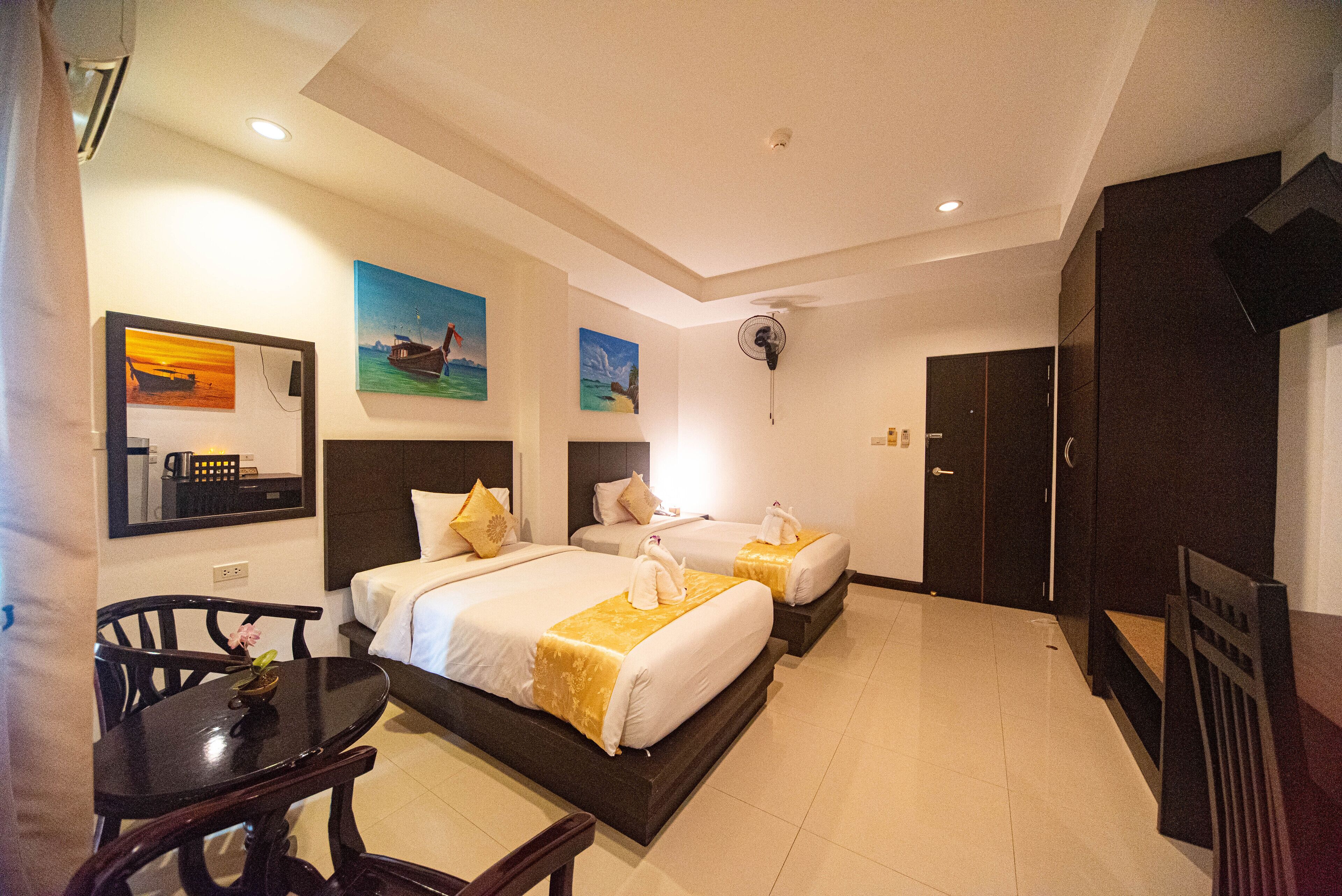 A hotel room with two beds, a dining table, chairs, and artwork on the walls.