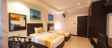 A hotel room with two beds, a dining table, chairs, and artwork on the walls.