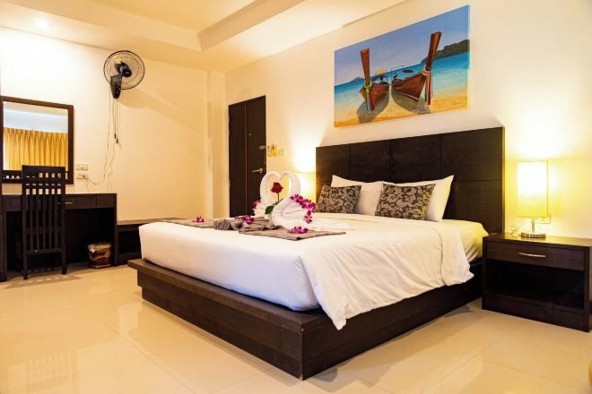 Habitación de hotel con una cama grande, un escritorio, una silla y un cuadro de una playa.