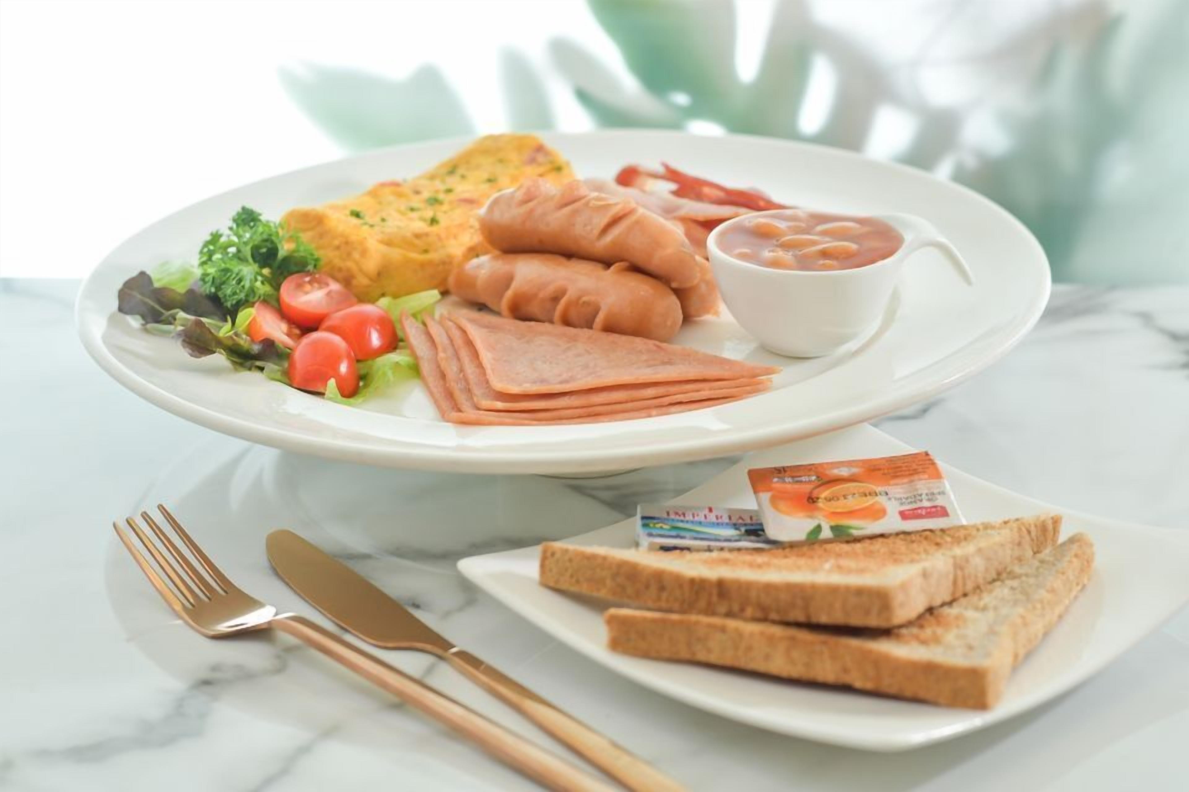 Une assiette de petit-déjeuner comprenant des toasts, des saucisses, une salade et un bol de soupe.