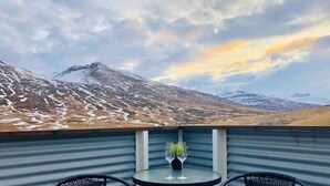 Een balkon met twee stoelen en een tafel, met uitzicht op een bergachtig landschap.