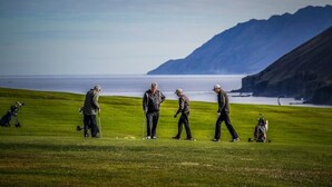 A golf course with players and golf carts, surrounded by a mountainous landscape and the ocean. - Hidden Cabin with outdoor hot tub (Ólafsfjordur)