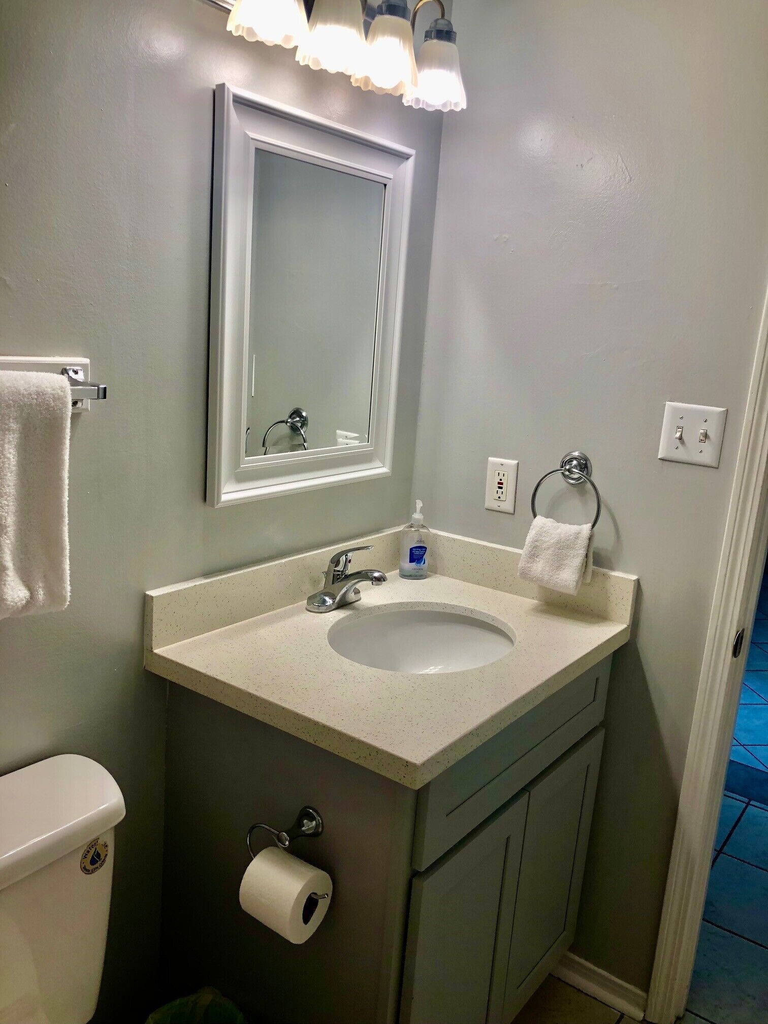 A bathroom with a white sink, a mirror, a toilet, and a towel rack.