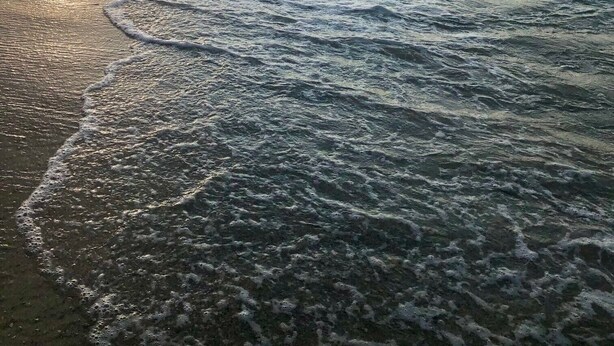 Una playa con olas suaves y cielo despejado.