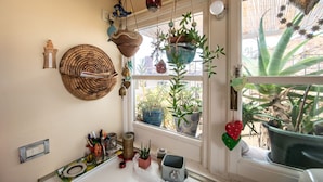 A kitchen with hanging plants, a woven basket, and various kitchen utensils on the counter. - Residenza al Pavone Luxury with Terrace (Lucca)