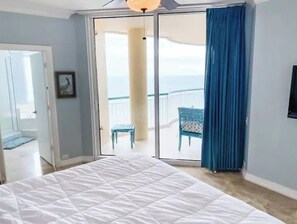 Relax in this serene room with a large bed, sliding glass door to a balcony, and a scenic view.