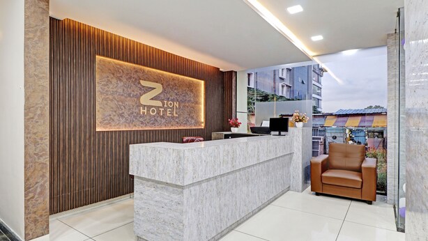 Uma área de recepção de hotel com balcão de mármore, painel de parede de madeira e uma placa com a inscrição "Z Hotel".