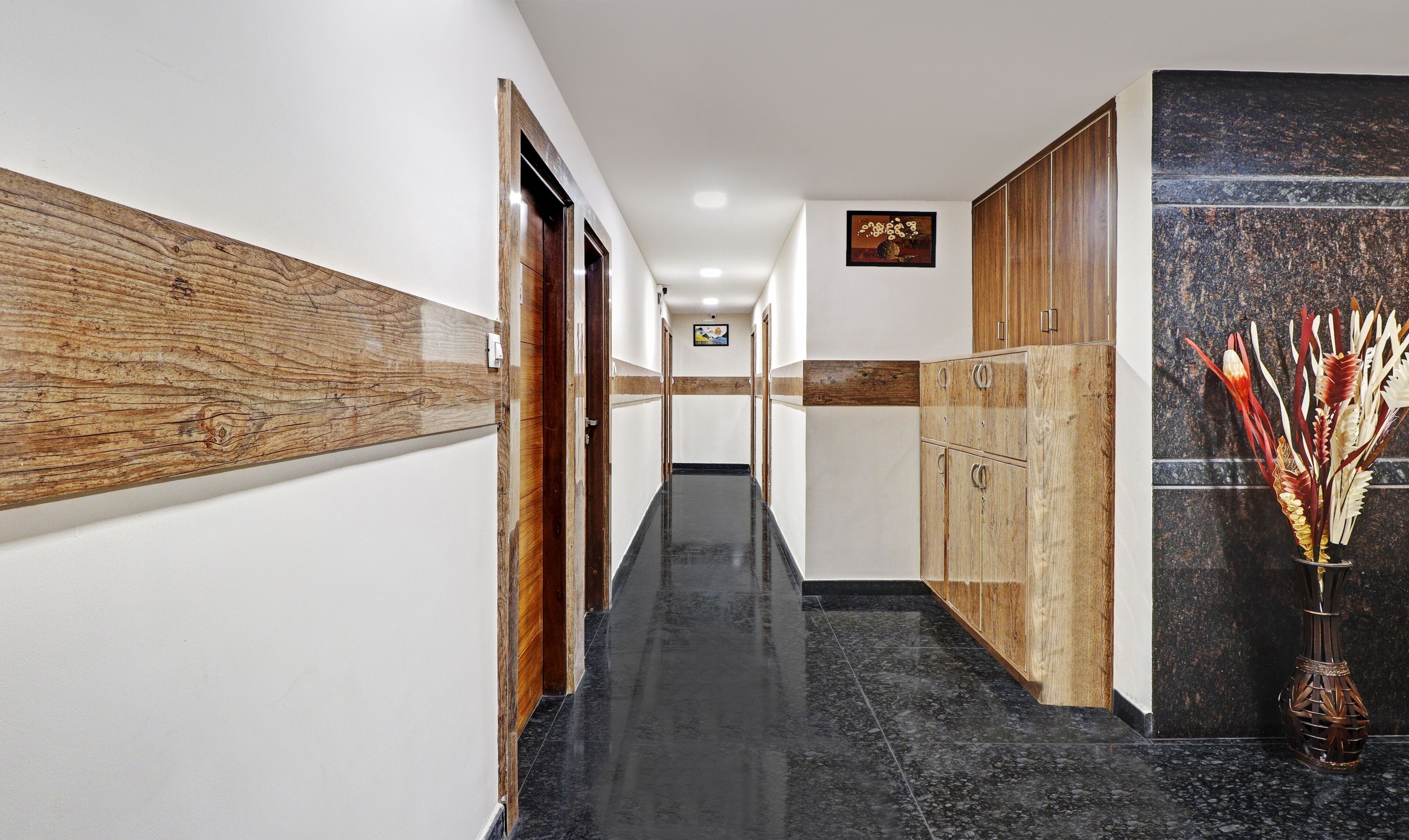 Un pasillo con paneles de madera, piso de mármol y un mueble de madera con herrajes metálicos.
