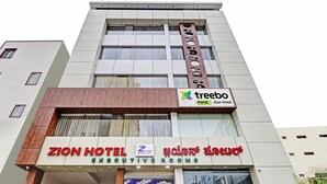 Um hotel com uma placa indicando Zion Hotel Executive Rooms e uma placa Treebo Trend.