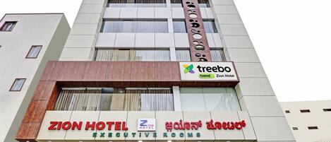 A hotel with a sign for Zion Hotel Executive Rooms and a Treebo trend sign.