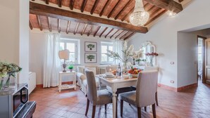A dining area with a wooden ceiling, a chandelier, and a table set for four. - Anna Farmhouse Apartment in Wine Resort in Lucca (Monte San quirico)