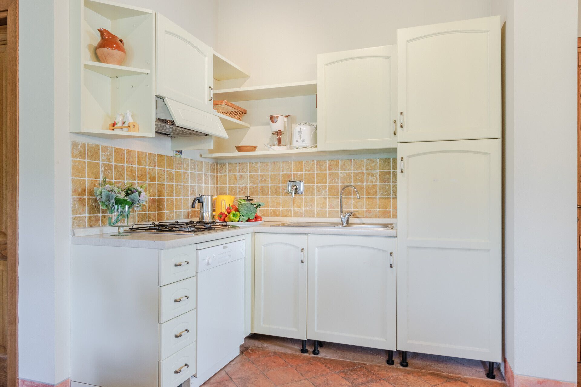A kitchen with white cabinets, a gas stove, a sink, and a tiled backsplash.