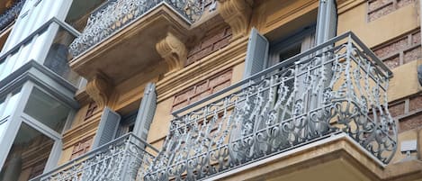 A building facade with ornate wrought iron balconies and a brick exterior.