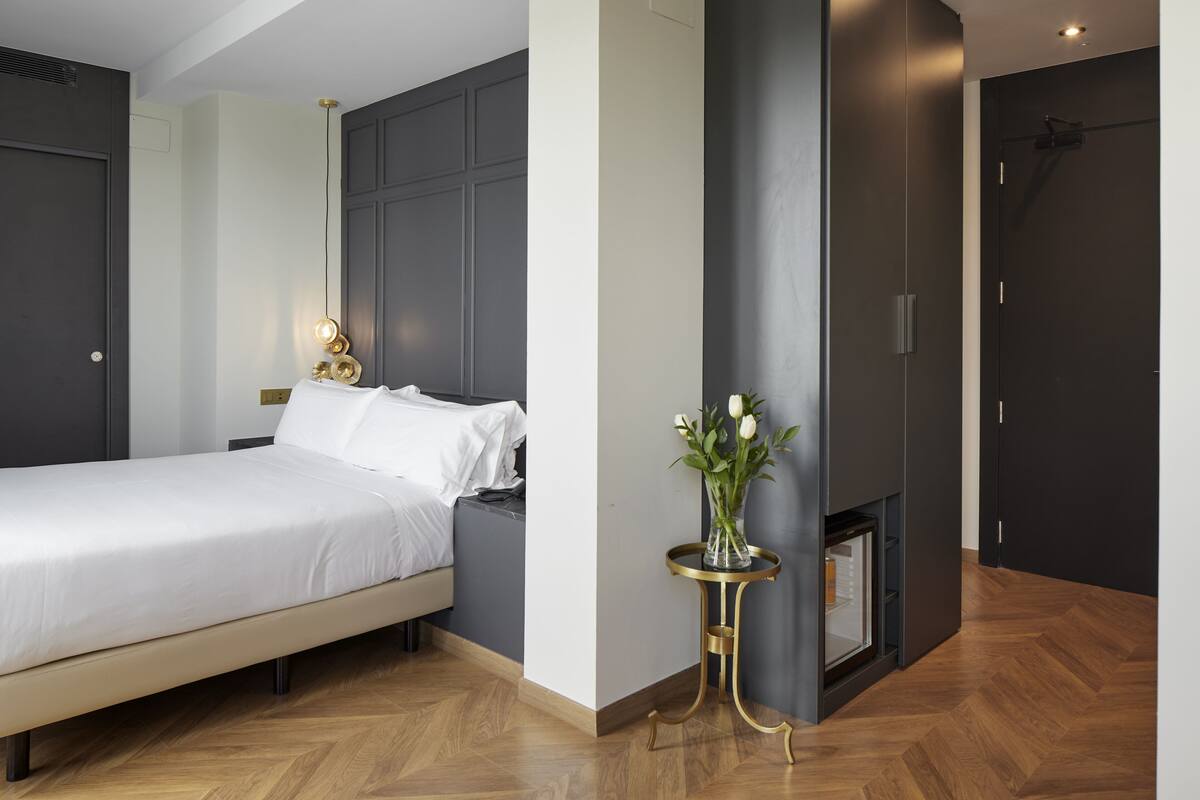 Quarto moderno com cama, mesa de cabeceira e um vaso de flores.