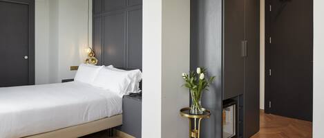 A modern bedroom with a bed, bedside table, and a vase with flowers.