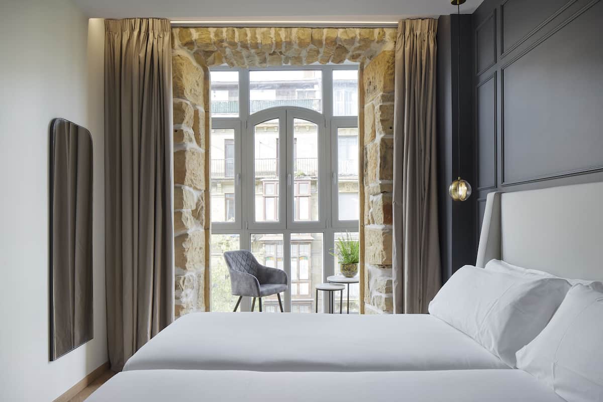 Quarto de hotel com uma cama grande, uma mesa pequena com uma cadeira e vista para a varanda.