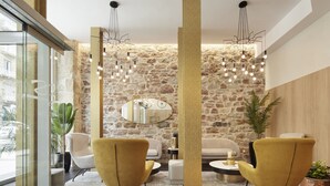 Un interior moderno con paredes de piedra, un espejo redondo y dos sillones amarillos.