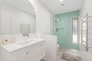 Een moderne badkamer met een witte wastafel, een douchecabine met glazen wanden en een wand betegeld met een visgraatmotief.