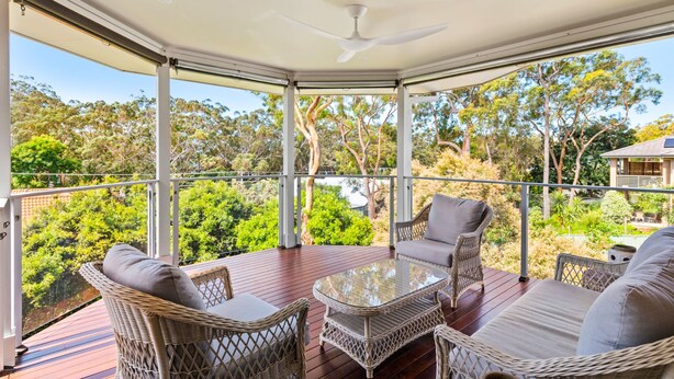 A covered outdoor area with wicker furniture, a glass table, and a ceiling fan. - Bonito near Bagnalls Beach Corlette (Corlette)