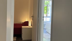 A narrow hallway leading to a bedroom with a red bed and bedside lamps. - Beautiful duplex with terrace and parking (Ivry-sur-Seine)