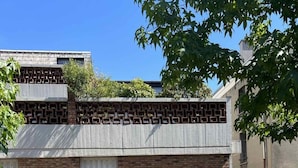 A brick building with a window and a door, surrounded by cobblestone pavement and trees. - Beautiful duplex with terrace and parking (Ivry-sur-Seine)