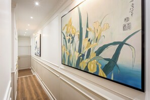 Un couloir avec une grande peinture de fleurs au mur, un plancher en bois et une porte au fond.