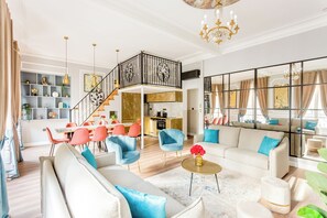 A spacious living area with a high ceiling, a staircase, and a kitchen in the background. - Merveil - Luxury Suite - Opera - Septembre I (Paris)