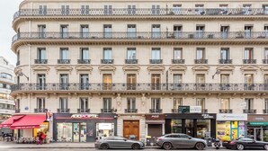 A multi-story building with a classical architectural style, featuring balconies, large windows, and a ground-floor storefront with various shops. - Merveil - Luxury Suite - Opera - Septembre I (Paris)