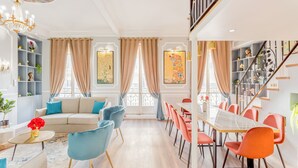 A spacious living room with a sofa, chairs, a dining table, and a staircase. - Merveil - Luxury Suite - Opera - Septembre I (Paris)