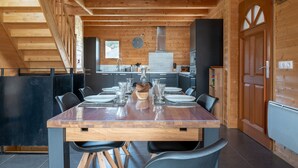 Un interior de madera con una mesa de comedor para seis, una zona de cocina y una puerta grande de madera.