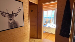 Interior de madera con un cuadro de ciervo enmarco, una decoración con forma de corazón y una cama con vistas.