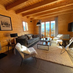 A cozy log cabin interior with a sofa, armchair, coffee table, and a TV. - Chalet Bolquera - Four Bedroom House, Sleeps 8 (Bolquère)
