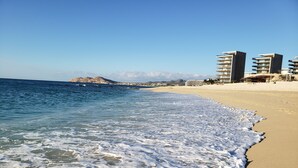 A beach with clear blue water, sandy shore, and buildings in the background. - Beautiful, Luxurious Puerto Vallarta Resort (Puerto Vallarta, Jalisco)