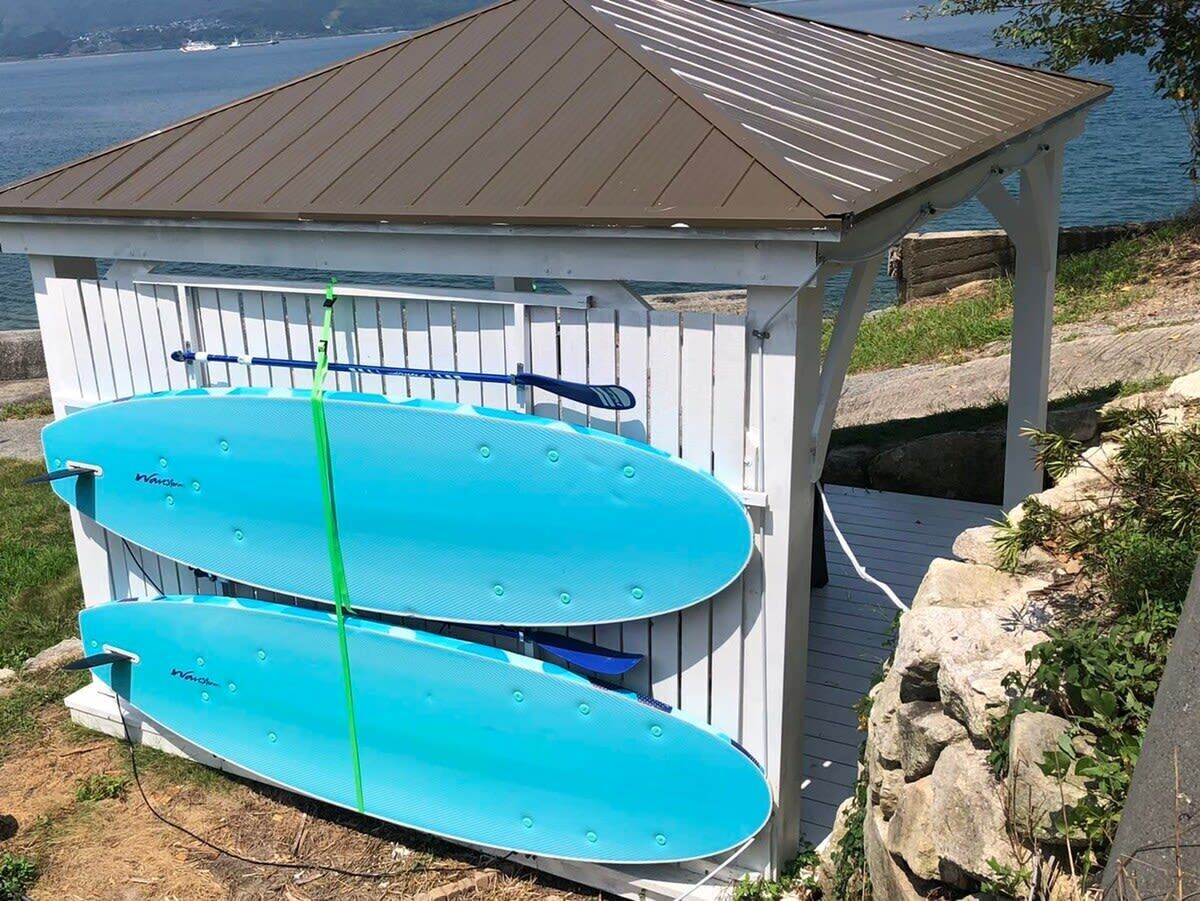 A small wooden shed with two blue surfboards inside.