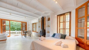 A spacious bedroom with a large bed, a wooden wardrobe, and a dining area with a table and chairs. - Villa Can Sarrio - San Carlos (Santa Eulària des Riu)