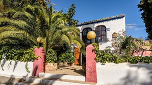 A building with a white facade, red pillars, and a wooden door. - Villa Can Sarrio - San Carlos (Santa Eulària des Riu)