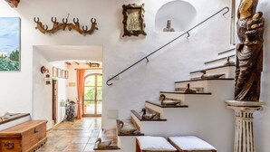 A staircase with a rustic design, a wooden bench, and a decorative wall with a statue. - Villa Can Sarrio - San Carlos (Santa Eulària des Riu)
