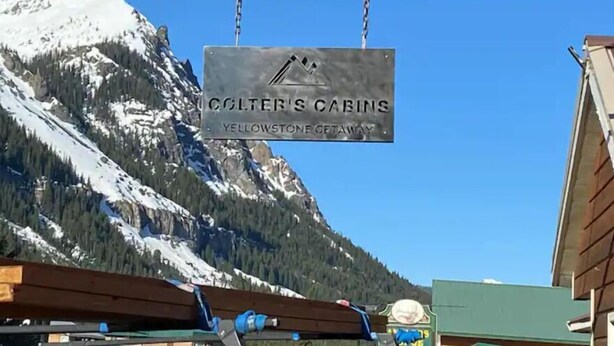 Señal de Colter's Cabins con montañas al fondo.
