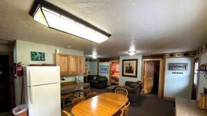 Cocina compacta con armarios de madera, un refrigerador y una mesa de comedor con sillas.